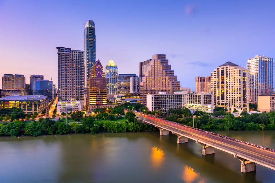 View of Austin, Texas skyline at dusk with Colorado River and bridge in foreground